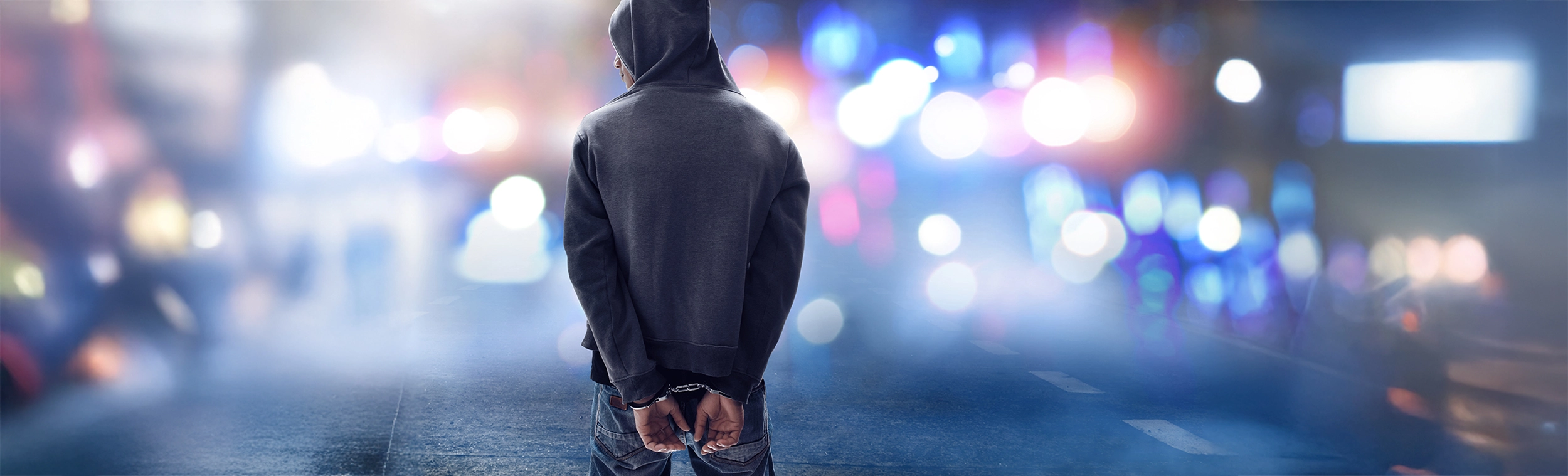 Dieses Bild zeigt einen Mann in Handschellen in einer abendlichen Stadtumgebung